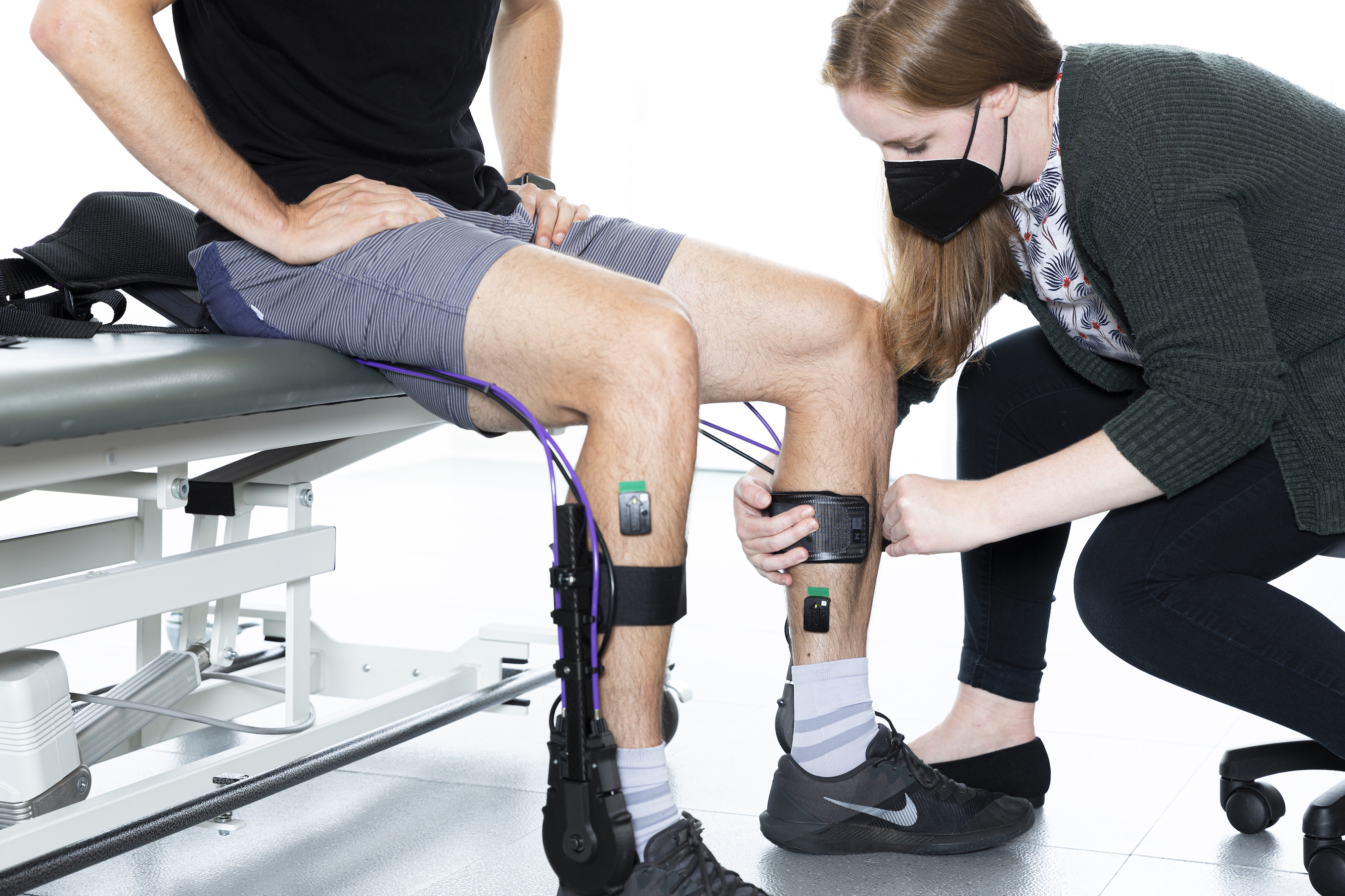 Female researcher adjusting the exoskeleton device in the calves