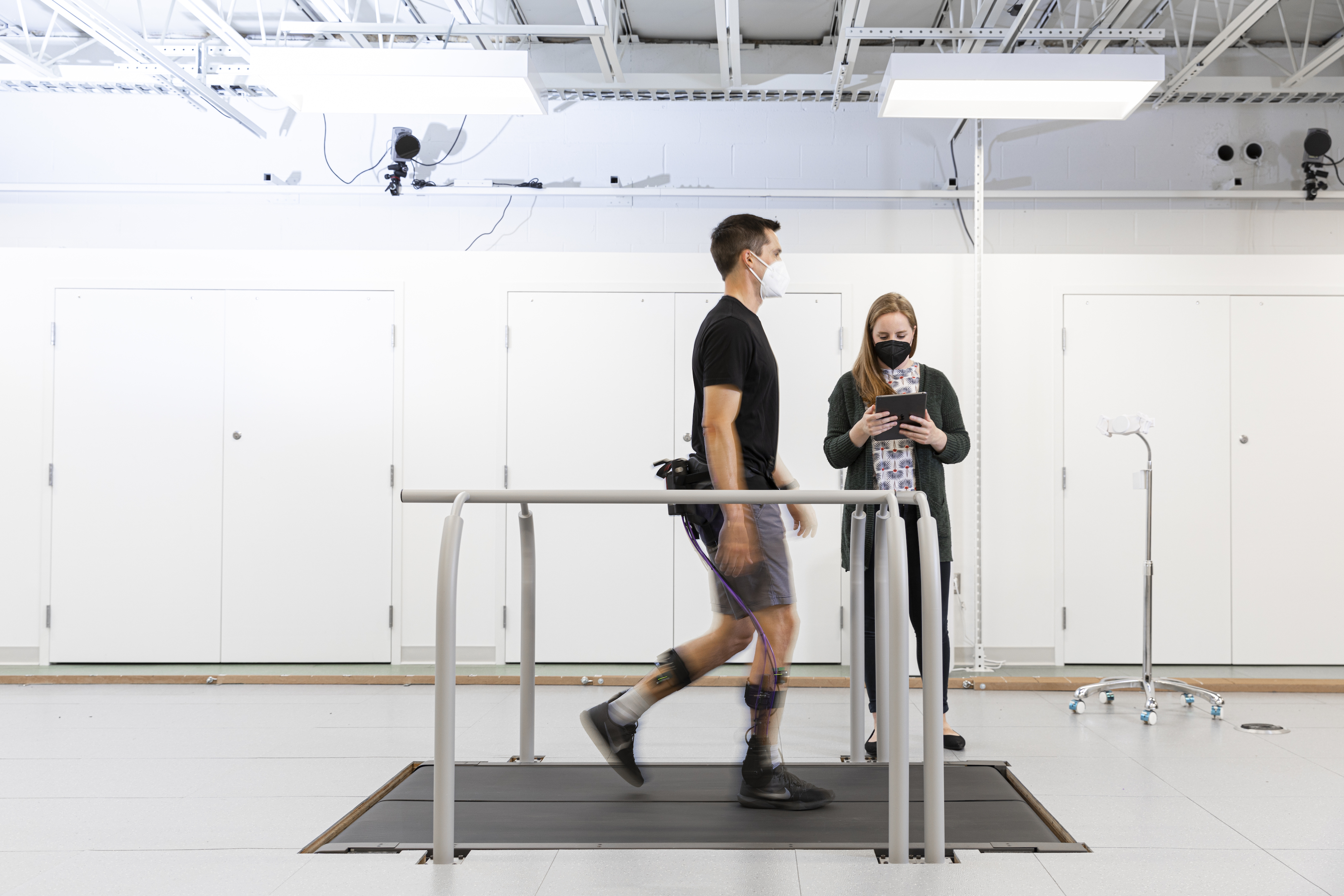 Man walks on a treadmill wearing an exoskeleton device around his hips and legs