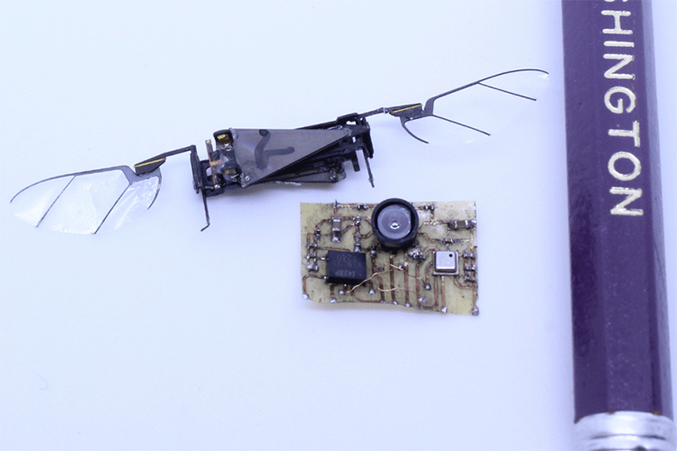 A sensor suite next to an insect robot with wings and part of a pencil for scale.