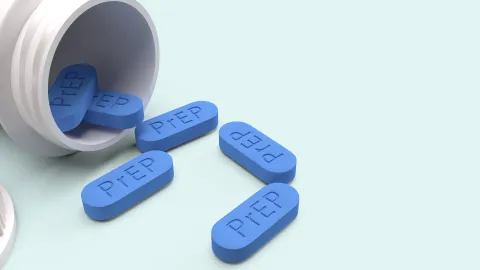 Pills with the word PrEP spill from an open container