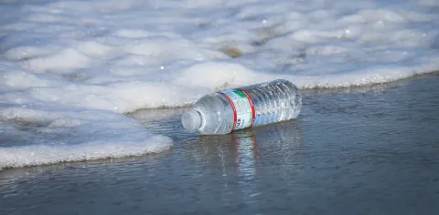 A plastic water bottle sits in the ocean surf