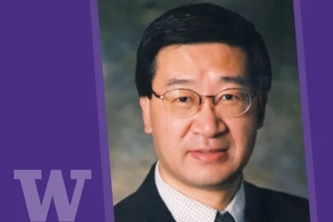 professional-style headshot photo of man in glasses and suit with UW logo in lower left