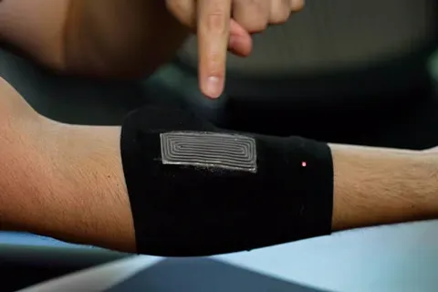 Close-up of a forearm with a black armband containing a sensor