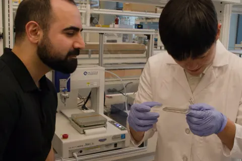 Mohammad Malakooti and Youngshang Han inspect the 3D printing quality of their new device that converts heat to electricity 