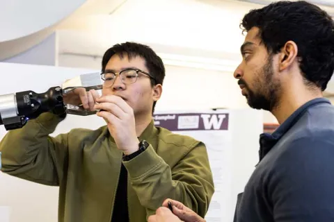 Two student researchers adjust a robotic gripper