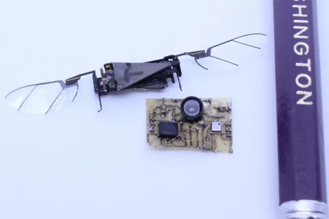 A sensor suite next to an insect robot with wings and part of a pencil for scale.