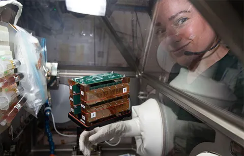 An astronaut next to a device floating in space