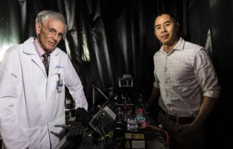 Two men posing next to 3D imaging machines