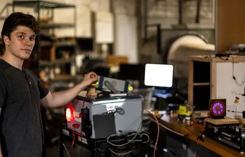 A person in a lab adjusting a device and looking at the camera