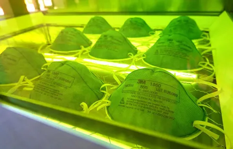 15 N95 masks inside a glowing green chamber