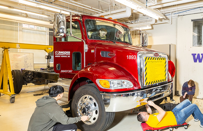 Students on the E-Truck team work nearby or inside a red truck.