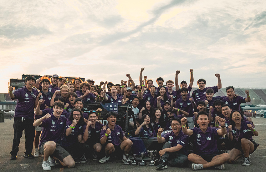 The Formula team smile and cheer around their car at the competition.