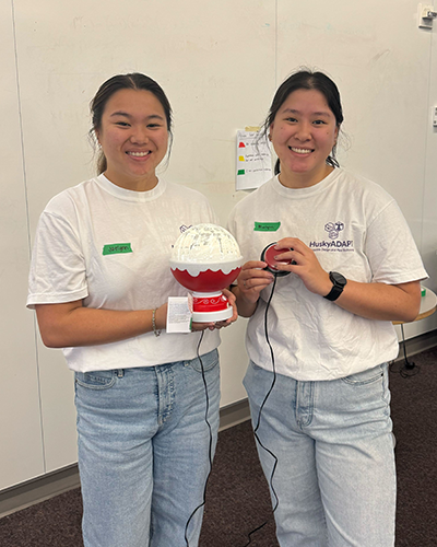 Jaelynn Hunt-Osburn and Maelynn Dank hold a switch-adapted toy that looks like a snow globe.