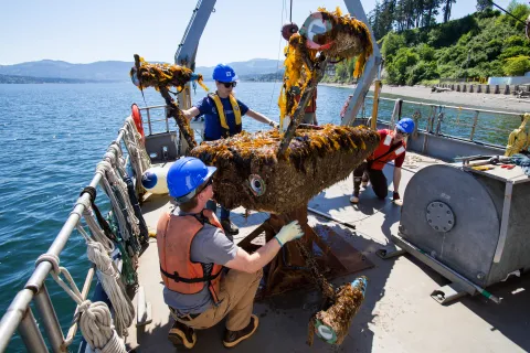 three researchers loading machinery on a ship