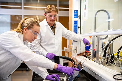 Two researchers in a lab looking at a laptop screen 